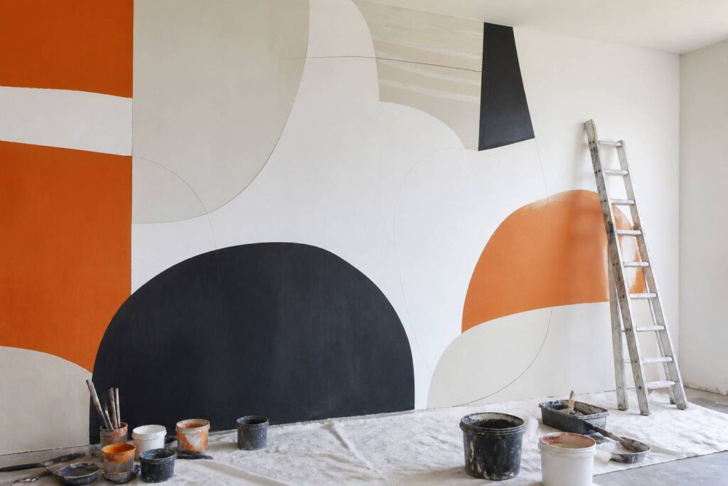 Fresque murale colorée en cours avec pots de peinture et échelle