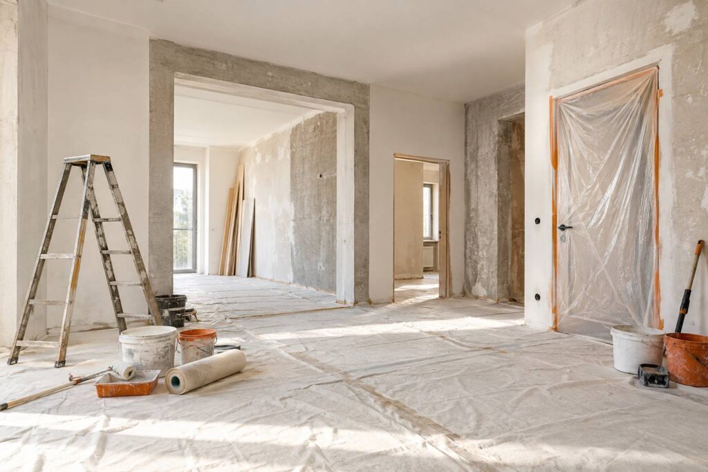 Appartement en renovation avec sol protege, escabeau et pots de peinture